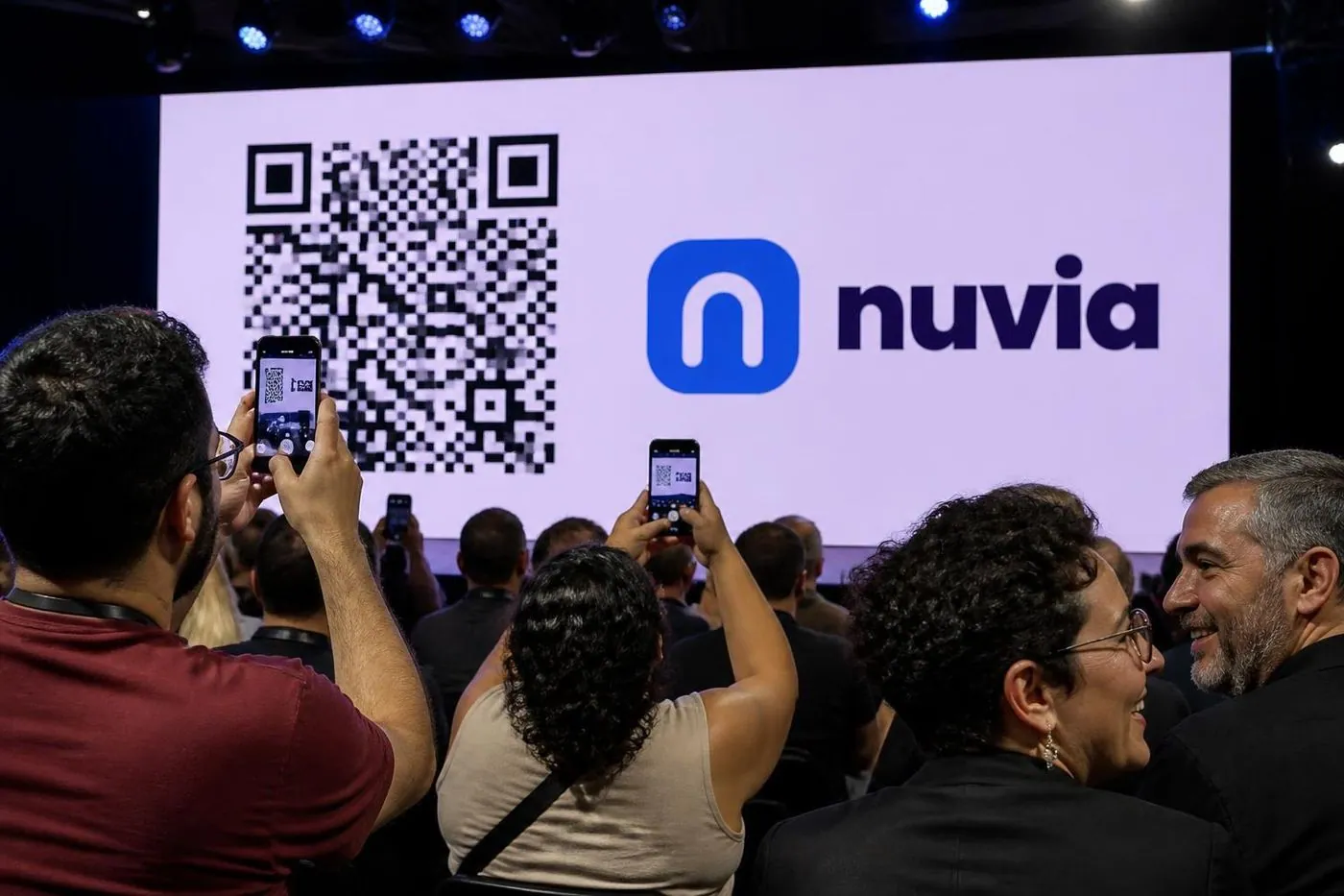 Plateia de uma convenção apontando o celular para o QR code no telão