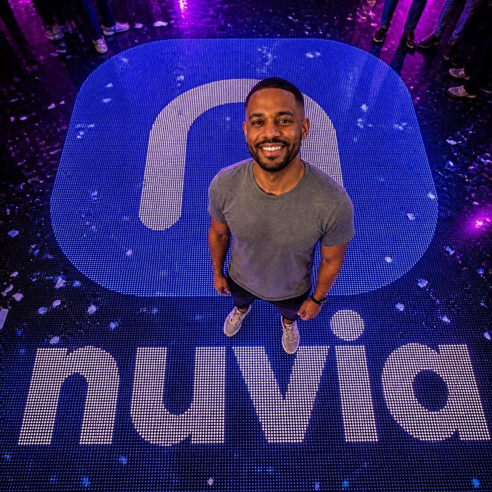 Exemplo com IA, vista de cima: convidado na pista de LED com o logo da marca fictícia nuvia