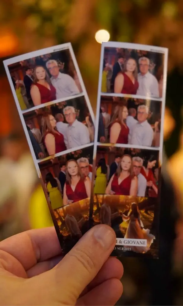 Tirinhas de fotos impressas na hora pelo totem, na mão de um convidado